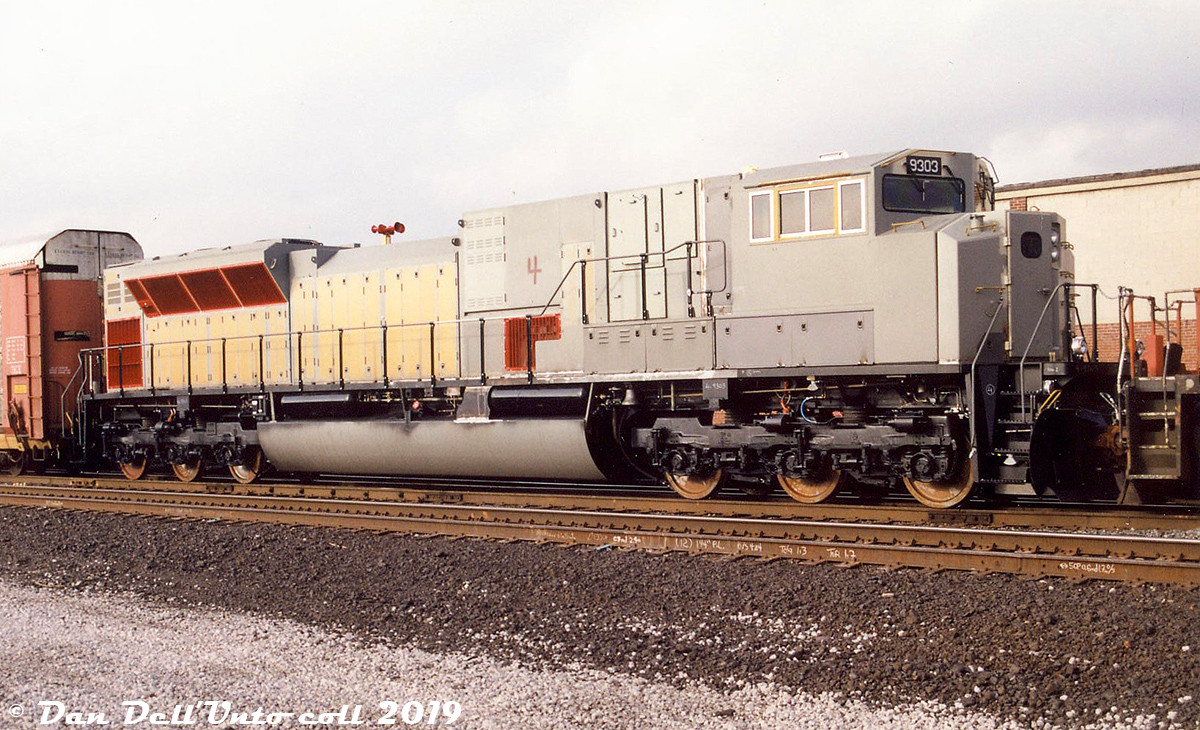 The final unit of Canadian Pacific's first and only order of the pure 6000 horsepower SD90MAC-H model, brand-new CP 9303 trails a freight at West Toronto, heading east for painting and final completion work. This photo from my collection acquired many years back is undated and unlabeled, but I suspect it may be a Tim Reid shot taken in either December 1999 or January 2000.

UP and CP both got on the high-horsepower bandwagon in the late 90's by ordering EMD's mighty SD90MAC units, promising to be the most powerful single-engined diesels built with EMD's newly designed 4-cycle 6000 horsepower 16-cylinder 265H engines. Initially CP ordered 61 of the "convertable" SD9043MAC units in 1998 (some of which were built by CP from kits at Ogden Shops) that were powered by the older 4300hp 710G engine. They were intended to eventually have the 710G's swapped out for the new 265H when it was ready (but that never ended up happening on any UP or CP unit). CP then placed an order for 20 of the new H-engined units, which was reduced to just 4 (numbered 9300-9303). They were built in December 1999 at EMD's GMD London plant, and forwarded in the unpainted state shown to Alstom in Montreal QC for final completion work that included painting. The first two reportedly began testing on CP in February 2000, and all four tested early on out west in the mountains.

CP was, to say the least, less than impressed with the reliability and performance of the big units, and no further orders for more would be forthcoming. The 6000hp units had a rather lackluster career in general freight service (when they were running, and not dead or in the shop) and after being parked and retired, all four were sold by CP to RB Recycling and cut up for scrap in 2011. Needless to say 9303 was the last EMD product CP bought for a long time, only coming back to the EMD table in recent years for ECO rebuilds.

The 4300hp units fared a little better, but most ended up being parked during a traffic downturn a few years back and were never reactivated (while older SD40-2 and AC4400CW units continued to soldier on in service). After being stored for many years and even being put up for sale, the remaining 58 units are being rebuilt by EMD/Progress Rail into CP SD70ACU locomotives, following the lead of NS rebuilding their ex-UP units.

Photographer unknown, Dan Dell'Unto collection.