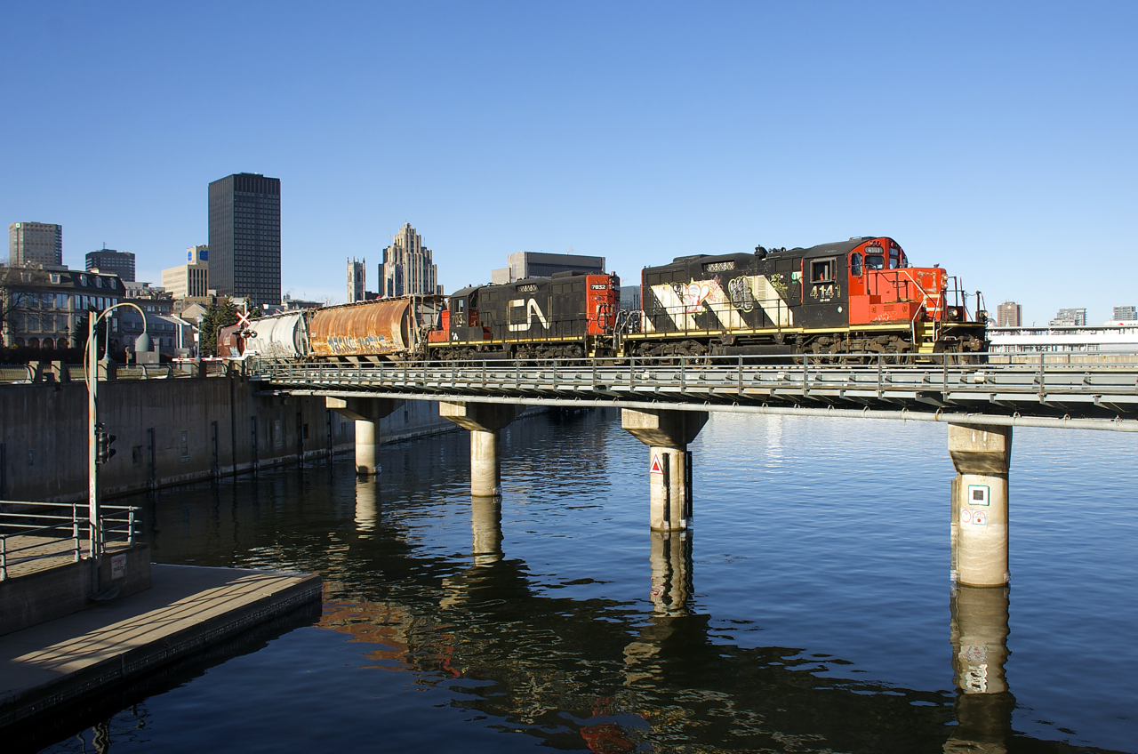 Two GP9's, including a tagged leader (CN 4141 & CN 7032) lead a long transfer out of the Port of Montreal, with most of the train comprised of grain empties.