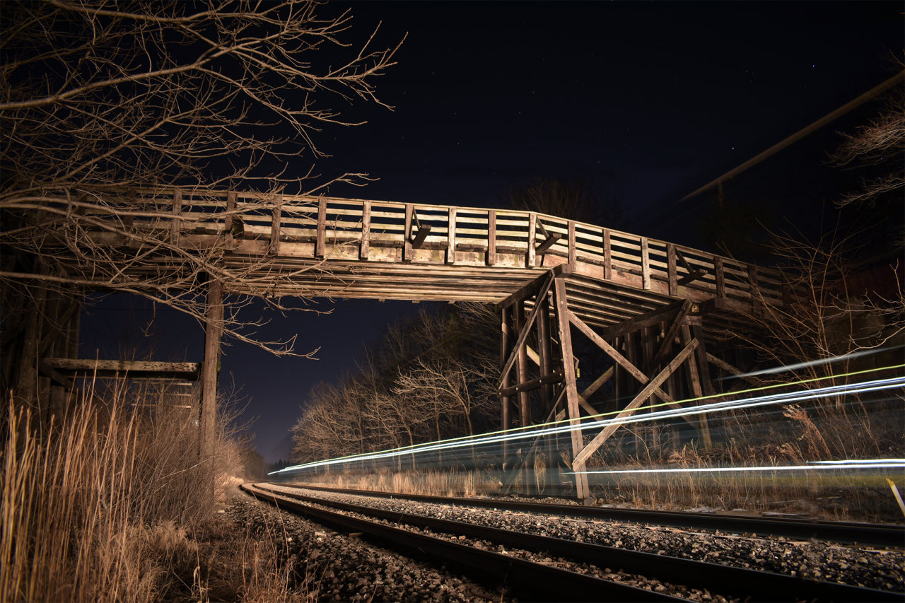 An unknown Eastbound CN train lights up the famous Denfield Road bridge on a crisp December evening before Christmas. The close paralleling of the CN and CP mains plus the little to no traffic on the bridge makes this a nice spot for one to come, sit and enjoy some railroad action.