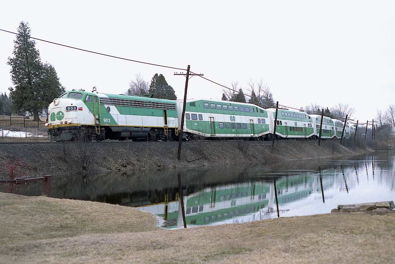 It is quite early in the morning, perhaps around 0600 when the second GO (of 5) of the morning leaves the 'compound' at Guelph Junction and heads eastward to begin the day at Milton. This view of the 903 was taken by the shore of the "Campbellville Pond" as the train is about to cross Guelph Line.