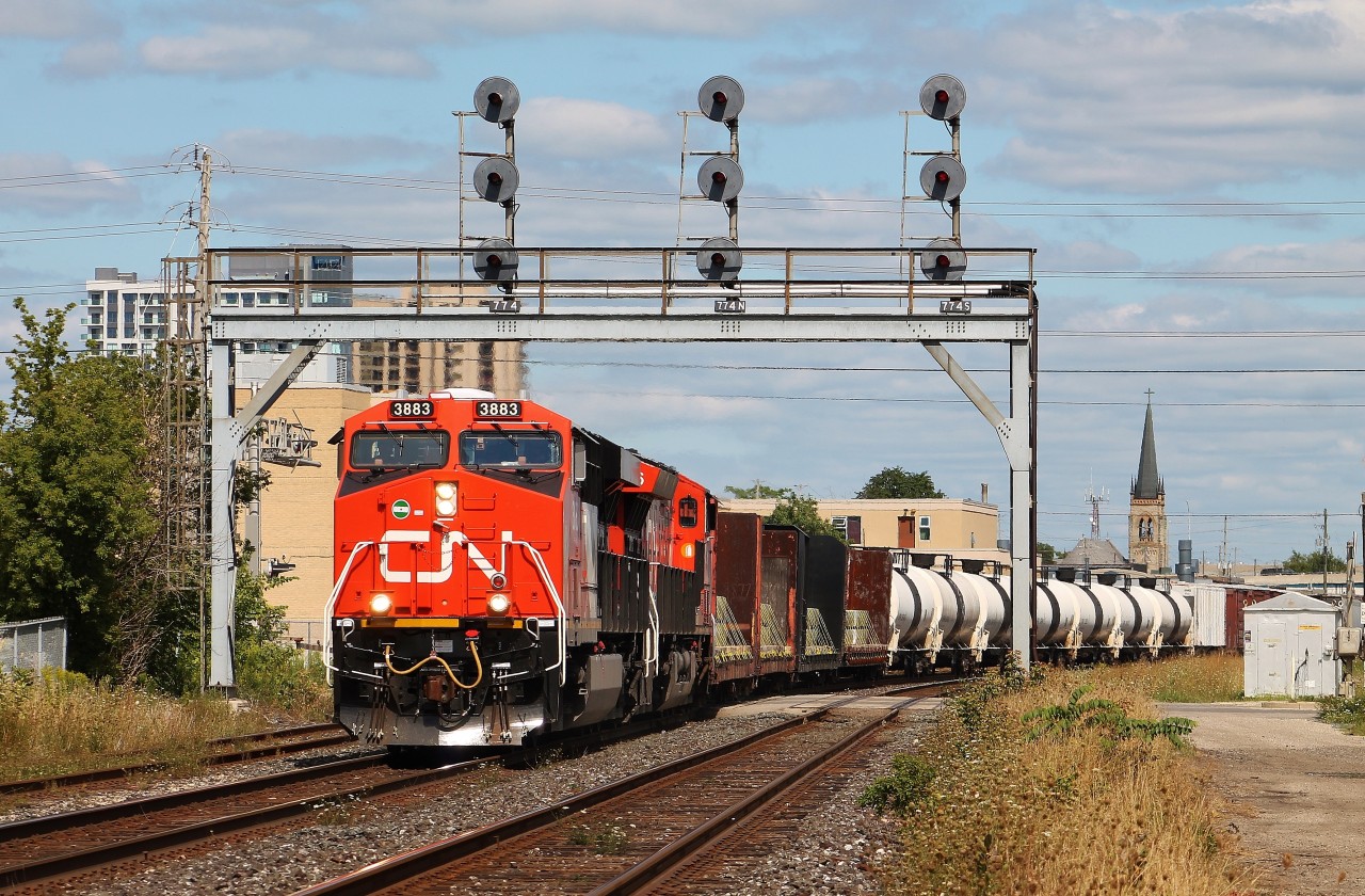 CN M385 passes under the searchlights at McLeod on the CN Dundas Sub. The steeple of St. Mary's Parish, built in 1856 can be seen in the background.