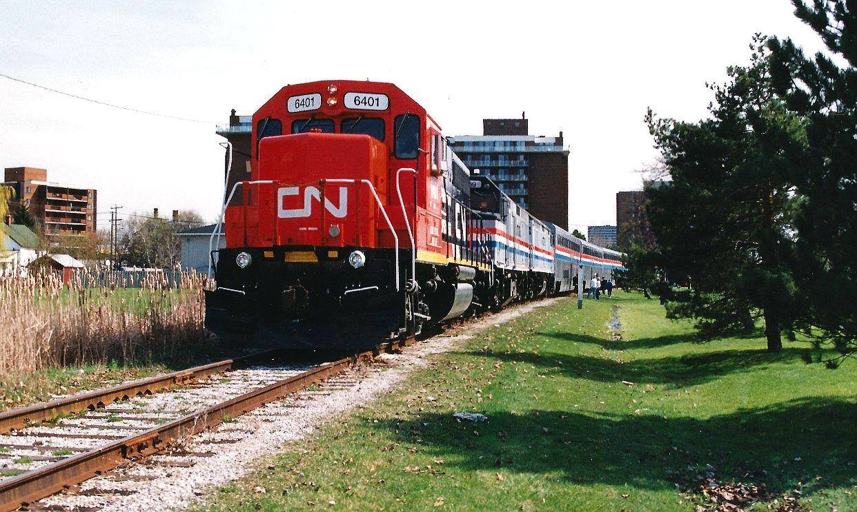 On May 5, 1995, CN had officially opened the new St. Clair River tunnel connecting Sarnia and Port Huron, Michigan. During the weekend of May 6-7 CN held many festivities in Sarnia and Port Huron to commemorate the event. CN had operated employee specials for workers across Southern Ontario as well as the US so they could attend the events along with their families. Both the American and Canadian passenger trains travelled down the Port Edward Spur in Sarnia to Centennial Park where the bulk of the festivities took place including live entertainment and displays. Here, the 20-car Blue Water Special with GT 6401, Amtrak 369 and Amtrak 297 are seen arriving near the Sarnia waterfront. This train hauled GT employees from Battle Creek, Lansing and Flint to the "Employee Day" events.