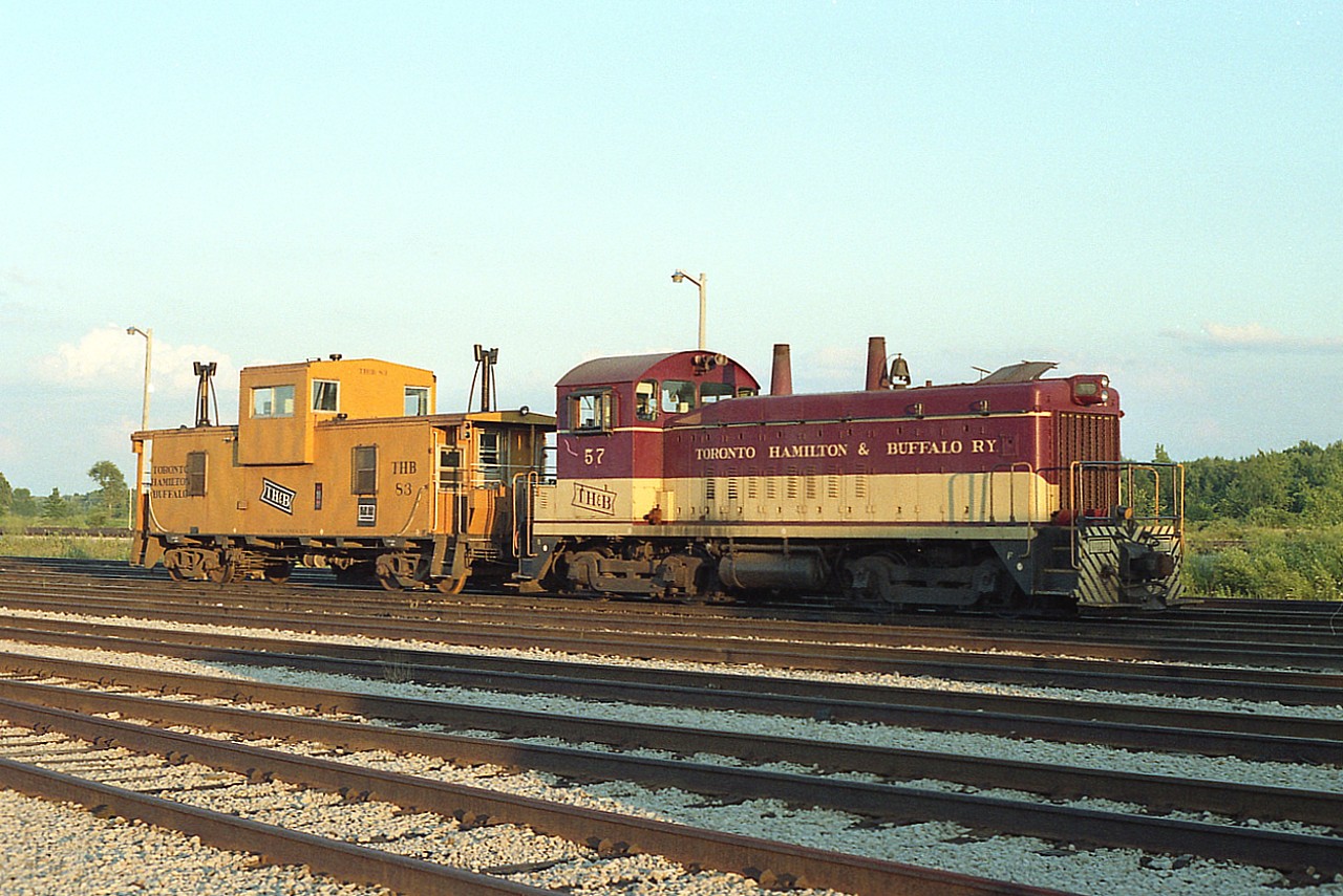 I still regret taking my time grabbing this image. I was not alert to how fast the shadow expanded and already was starting up the locomotive while I was looking around the yard. Oh well. Can't be helped. This view of TH&B 57 and van 83 was taken late day on a Sunday as it was a habit to go out and wander around after the heat of the day had passed.
TH&B 57 was sold to GMD in London in May of 1989.
The caboose was apparently scrapped in 1995.  Real shame.