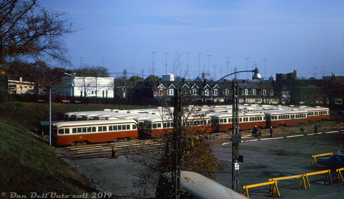 The opening of the Bloor-Danforth subway line in February 1966 put a lot of the TTC's older PCC streetcars out of work, notably most of the air-electric cars in the A1-A5 classes (numbered 4000-4299, built between 1938 and 1945). Many of the surplus cars were initially stored at carhouses and yards around the system pending possible resale to other transit agencies, while some remained active. During an Upper Canada Railway Society visit for a tour of Hillcrest Shops, some of those surplus PCC cars are visible outside, stored on temporary tracks in Hillcrest Yard. Shop employees are busy laying and welding rail together on the old recreation field at the northeast corner of the property (near Davenport and Bathurst) to lay temporary tracks to store them out of the way on. Car 4017 (a 1938 A1-class PCC) is pictured on the left in the closest row of cars.  Alas, since many other North American agencies had already abandoned or replaced their streetcar systems with buses, there wasn't too much of a demand in the market for secondhand streetcars. About 141 cars were sold to Alexandria, Egypt in 1966 and 1968 and shipped overseas, and 9 other cars sent to an agency in Mexico in 1971 (both groups including some secondhand ex-Cincinnati A10 cars), but almost all of the others were scrapped. The particular ones stored here don't appear to have been resold and most were cut up around the fall of 1969 (aerial imagery shows at least 60 PCC's had been stored in this area in 1968 and 1969, with all cleared out by 1970). A few of the higher-numbered cars from the A2-A5 classes remained in service until the last retired in 1972. TTC's first PCC, car 4000 (that wasn't in this lot, but was on-site for attendees on this day, as well as Peter Witt car 2766) was retained as a training car and eventually donated for preservation. It's currently a part of the Halton County Railway Museum's collection, and the only one of the original A1-A5 PCC cars to survive.  John F. Bromley photo, Dan Dell'Unto collection slide.