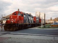 The CN 15:30 Kitchener Job has a lengthy train destined for Elmira as it crosses Regina Street in Uptown Waterloo with GP9RM's 4111 and 7037. At the time, it wasn't common for this assignment to operate with two units, as most jobs out of Kitchener usually just ran with one during the mid-1990's. However, due to the 8 hoppers for Nutrite in Elmira, the crew opted to use two as they also had a tanker for Sulco as well as caboose #79905. Most trains on the spur weren't this lengthy at the time, however seasonal demands in the spring and fall would dictate otherwise on occasion.