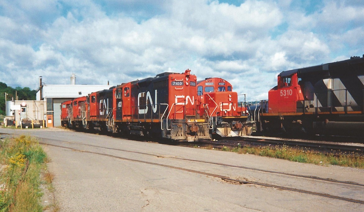 A Saturday morning in 1993 finds CN’s Stuart Street yard shop tracks full of units awaiting their next assignments. The units included from left to right were; SW1200RM’s 7103, 7104, 7307, 7314, GP9RM’s 4127, 4136, 4101, SD40-2(W)’s 5299 and 5310. Also, around the shop facility that day were SW1200RS’s 1355, 1369 and 1375. As well, SW1200RS’s 1359 and 1360 were observed switching the yard. I also have in my notes that there were five active CN cabooses around the yard; 79648, 79853, 79473, 79783 and 79482.