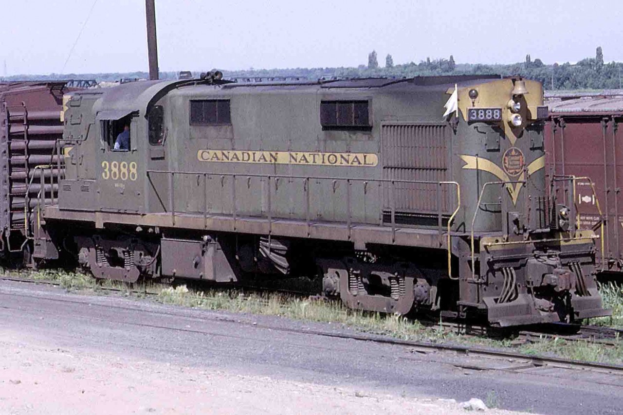 A few days ago, I posted an image of CN 2020 with an RS-18 lurking in the background. Here's that unit, the 3888 switching in Ottawa, Ontario on the morning of Tuesday, July 5, 1966. It was working the switcher from CN's Walkley Yard to the CP interchange at Ottawa West while serving other CN customers in the Chaudiere Flats area. Later, at the Moncton Shops, the unit was equipped with A1A trucks from a retired MLW RSC-13 and its V12 re-rated to 1,400 horsepower because of the lighter-duty traction motors. It was renumbered 1783 and assigned to Halifax for a time. That's CP's Prince of Wales bridge from Ottawa West to Hull West barely visible above the unit.
