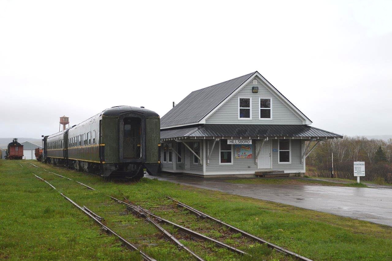 The past for this former Salem & Hillsborough Railroad seems about as dreary as the weather on the day when I paid this place a visit. Thru the miserable cold, wind and rain we can see the former tourist train office, a few static cars and the newly built engine house in behind.
This tourist road once was home to a handful of locomotives and was fairly active. But in 1994 a disastrous fire, due to arson, destroyed or badly damaged most of the equipment and brought the old S&H to its knees. Volunteer staffers were deflated and the operation became dormant. 
There has been no public train rides since 2004.
However, in 2005 the operation was reborn as the New Brunswick Railroad museum, operated by the New Brunswick division of the CRHA. Well worth the visit.