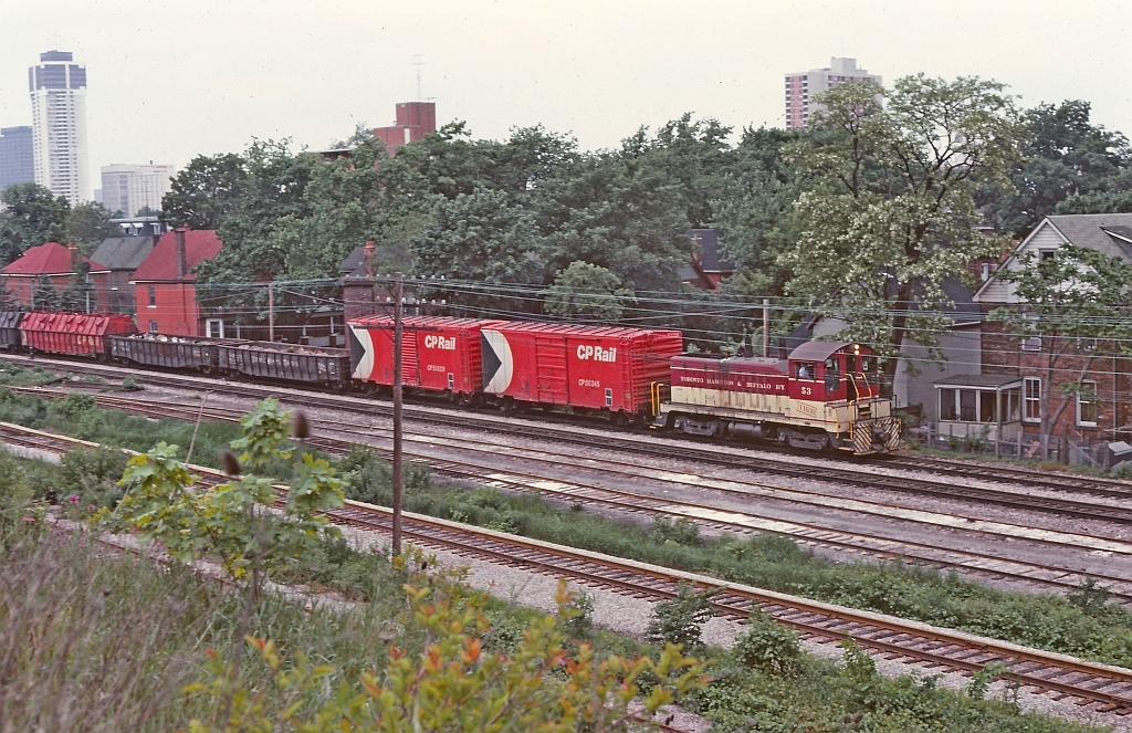 Thanks to Ron Tuff for this image. TH&B 53 doing a routine chore of a transfer from Aberdeen yard to Kinnear yard. Ron noted on the slide that this was near Wentworth St. My memory is a little hazy but the tracks in the foreground perhaps are the CN Hagersville sub and the small interchange that TH&B had with CN. Also at one time there was a freight shed in the area.