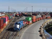Working the north end of CN’s Brampton Intermodel Yard on the sunny spring afternoon of May 5 2019, GMTX 2163 and CN gp9rm 7258 with the 15th Anniversary logo are seen shoving a stash of loaded container cars onto the unloading track while yet another CN Gevo is seen slowly approaching the scene on the third main track with yet another container manifest which will soon be unloaded here. <br> If you look towards the containers spotted in the holding tracks behind the yard tramp you’ll also be able to notice the stash of CN buisness coaches resting directly at the start of holding track #6 I believe. Those were set off only a couple hours previously by CN 148 and fellow contributor Steve Host actually managed to shoot them coming down on 148 earlier that day. I’ll make sure to include a link to his photo in the first comment below.