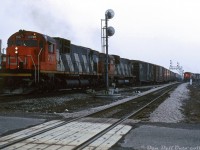 An eastbound freight rolls through Goreway interlocking (and over its namesake road crossing) on CN's Halton Sub with CN C630M's 2026 and 2004 in the lead. In the background, a set of power (M636, M420W and HR616) sits on one of the leads to Brampton Intermodal Terminal, probably waiting to leave for MacMillan Yard for servicing after dropping their train at BIT. <br><br> Built in the late 1970's on what was once Chinguacousy Township farmland, Brampton Intermodal Terminal is CN's main GTA-area intermodal terminal and handles traffic going to and coming from Western Canada, Eastern Canada, and the USA. BIT was expanded at various points in time to handle the growning volume of intermodal traffic (although right now it's constrained by development on all sides, and CN is looking at opening another terminal in Milton). The twin leads at the south end connect with CN's Halton Sub at Goreway and Torbram. <br><br> The earliest mention of BIT I've found is in some 1975 City of Brampton council minutes. It had been reported as various names before it opened, including "Malport Intermodal Terminal", "Bramalea Intermodal Terminal" (Bramalea amalgamated with Brampton in 1976), "Brampton Intermodal Terminal", and most curious, "<a href=https://www.peelregion.ca/council/council_minutes/1970s/1978/rcmin19781026.htm><b>Bramport Intermodal Terminal</b></a>". It appears to have opened as Brampton Intermodal Terminal in 1979 though (for a 1981 aerial view showing how it originally looked, see <a href=http://jpeg2000.eloquent-systems.com/toronto.html?image=ser12/s0012_fl1981_it0051.jp2 ><b>here (on the left)</b></a>. There was a "ConPort" terminal at MacMillan Yard that likely handled what container and piggyback traffic there was prior to BIT opening (located at the north end of the yard near the old piggyback terminal). <br><br> <i>Keith Hansen photo, Dan Dell'Unto collection slide.</i>