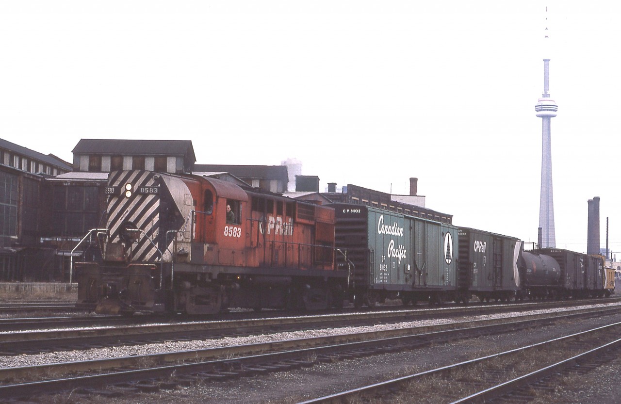 Thank goodness for the CN Tower. This landmark was the only clue I had as to where I shot this, and outside help steered me to pinning this location down to somewhere west of Strachan and east of Pirandello St. The view is looking east of course and the structure in the background along with the stacks is the old Toronto Refiners & Smelters lead foundry. This plant closed and faced demolition in the mid-80s and now has finally been cleaned up to allow for future development. In Toronto that usually means glass towers.
Nice old boxcar. Just out of sight behind the caboose should be the Strachan Av watchmans tower if I have this pegged correctly. It was one of the last of the once plentiful railroad crossing structures.