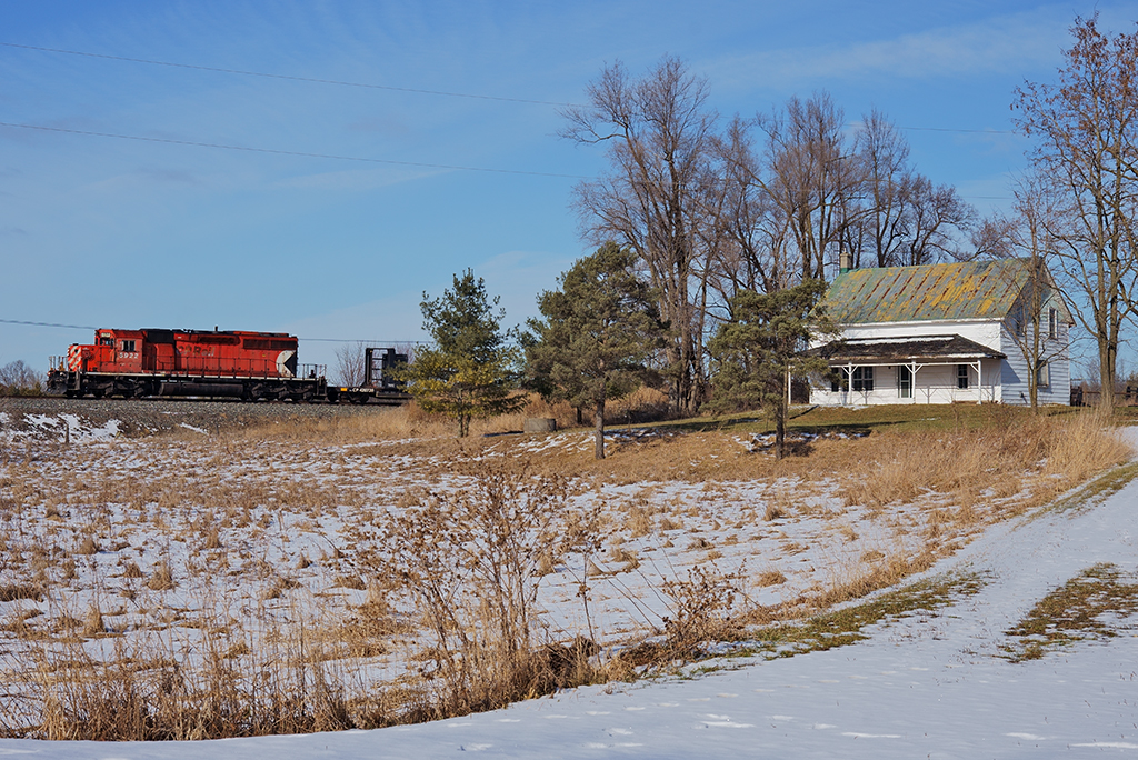 After dropping rail on the south track between Obico and Cooksville, CP 5922 West provides the horsepower for this ribbon rail train passing many rural country side homes like this one on their way to Wolverton.