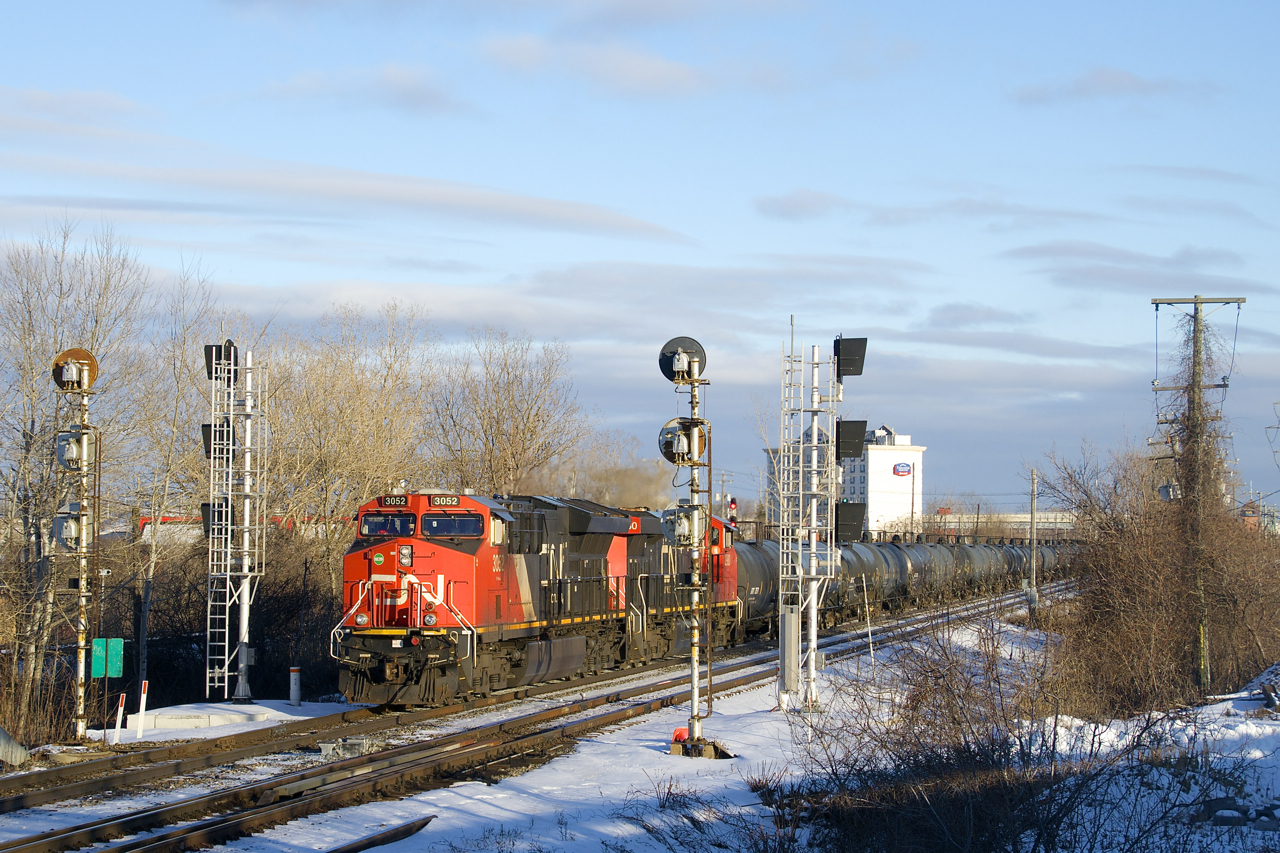 CN 377 is bathed in some nice winter light as it passes endangered searchlight signals at CN Dorval with CN 3052 & 2980 for power and 129 cars.