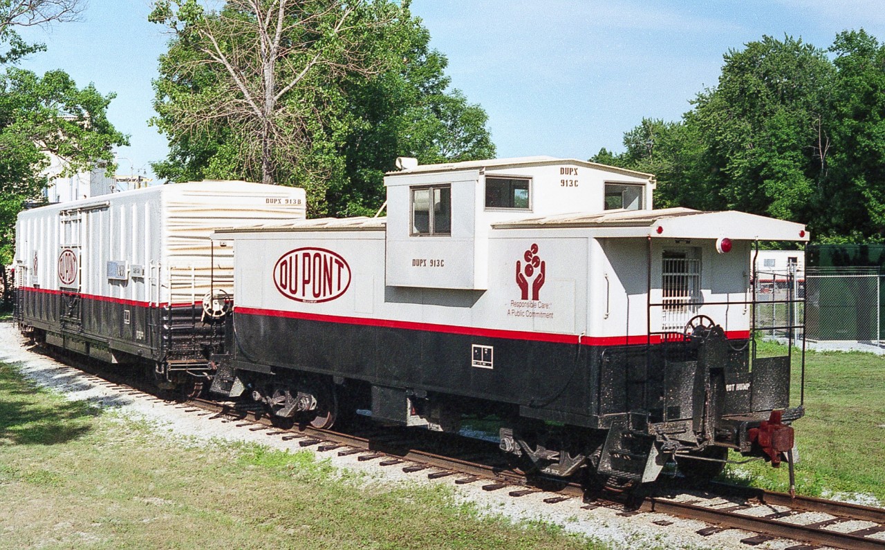 A change of pace from 1993 in Sarnia's Chemical Valley. One of the few times I carried my camera in the duffle bag. The day I took this image, I knew these were sitting here, so I was prepared. Brought to the Dupont of Canada Sclair Works in Corunna, for a planned TransCAER meeting. These would involve not only the host industry, but nearby industry, plus fire, police and other responders, plus representatives from local railways (in this case, CN and CSX). There are actually 3 cars here - the International Car caboose 913C, the outside-braced 50 foot cushion car 913B, and the DUPX tank car 912. The tank car, unfortunately out of sight on the backside of the curve, is for demonstration and training, as it has been equipped with multiple domes, valves and interior walkways. It is numbered 912 so as not to be confused with several other, similar cars, numbered 911 under a couple of ownerships. The boxcar not only carries further demonstration features, but has the generator to power the caboose (heating, lighting etc). These 3 cars were based somewhere in the USA and this was the 2nd time that I had encountered them in Canada. Taken with my Canon TX from the cab of some obscure CSX GP38 while working the 4pm " hill job".