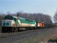 In the late 70's and into the 80's, power-short CP found a convenient source of extra power in the form of under-utilized GO Transit commuter units. Instead of sitting around Guelph Junction or Willowbrook after working a week of 9-to-5 commuter service hauling passengers on the Milton or Lakeshore commuter lines, CP would often round up a bunch of GO units on Friday evening and send them on their merry way for a Toronto-Montreal-Windsor-Toronto weekend trip hauling 900-series freights, often with a CP unit or two thrown in for good measure. As long as they were back in time for Monday morning rush hour, the motive power guys at CP wouldn't get any angry phone calls from GO wondering where their commuter power was.<br><br>Here, the CP conductor gives a wave out of the cab of GO Transit F40PH 513, leading GO GP40-2W 700 and CP GP35 5025 on train #903 westbound through Campbellville on the Galt Sub, with no shortage of CP autoracks on the head-end. GO power was still being leased by CP in the late 80's and in the early F59PH era when some of GO's "40" series power was surplus. CP even managed to send a few GO units as far west as Alberta and Saskatchewan. Eventually the old GO fleet was dispersed to CN, Amtrak and EMD, and that was the end of CP leasing GO power on weekends (GO elected not to lease CP any of their brand new F59's to run ragged in weekend freight service).<br><br><i>Reg Button photo, Dan Dell'Unto collection slide.</i>