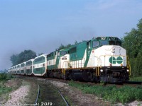It wasn't very common to see the new GO Transit F59PH units operating with older power, partially because of the short overlap of only a few years that both co-existed on the roster, and partially because the F59's were more than capable of handling a train themselves and providing their own HEP, but it did happen as evident here!
<br><br>
GO Transit GP40-2W 707, running out its final miles on GO just a few months before retirement, double-heads a 10-car bilevel consist with F59PH 526 on train #1908, heading eastbound over Clarkson Road North east of the GO station just before 9 in the morning. The service track to CN's Clarkson Yard, the east end of the wye and Petro Canada's Clarkson refinery can be seen in the foreground.
<br><br>
By this point in time GO had amassed a fleet of 42 F59's in three orders, allowing it to sell both its GP40TC's (to Amtrak in 1988) and F40PH's (<a href=http://www.railpictures.ca/?attachment_id=31509><b>to Amtrak in 1990</b></a>). Their GP40-2W and rebuilt GP40-3's remained on the roster, often leased out to CP for freight service, but around the fall of 1991 ten GP40-2W's including 707 would be <a href=http://www.railpictures.ca/?attachment_id=38049><b>sold to CN for freight</b></a> use and renumbered above their own 9600-series units (a lone unit, 703, was sold to Tri-Rail). 
<br><br>
The ex-Rock Island GP40-3's would solder on for a few more years (often being leased to power-short CP for freight service) before being traded in to GMD on the last order of F59's in 1994, giving GO a solid roster of 49 F59PH units. Aside from a sale of 4 surplus units to TRE in 1997, the fleet of F59's would remain as GO's sole power until the first new MP40 arrived in the fall of 2007.
<br><br>
<i>Peter Jobe photo, Dan Dell'Unto collection.</i>