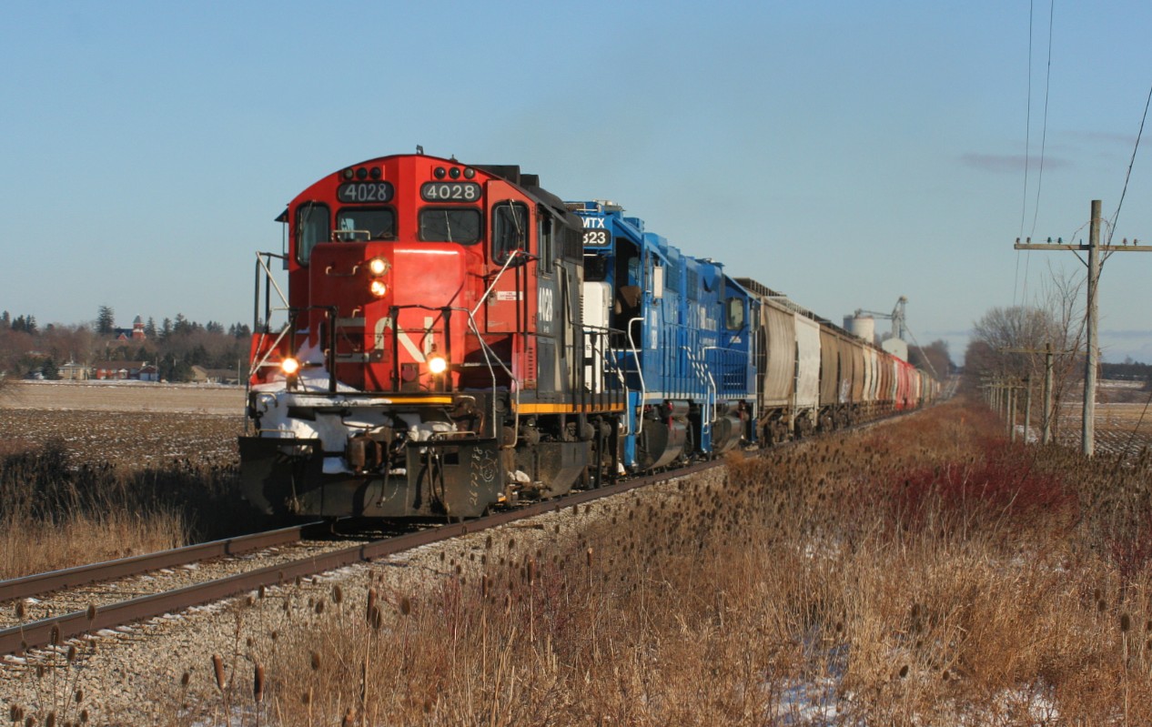CN L568-13 with GP9RM 4028, GMTX 2323 and GMTX 2279 are just west of the town of Shakespeare, which can still be slightly seen to the left, as they head westbound on the Guelph Subdivision to Stratford. All of the cars were later set-off at Stratford for the Goderich-Exeter Railway.