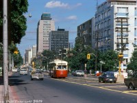 TTC PCC 4561 (an A9-class streetcar originally bought by Cincinnati in 1947) heads west in traffic through Midtown Toronto on St. Clair Avenue, operating on a westbound/northbound Rogers Road streetcar bound for <a href=http://www.railpictures.ca/?attachment_id=35859><b>Bicknell Loop.</b></a> The office buildings and highrises around Yonge Street are visible in the background. To the north (left) is the upscale Forest Hill area full of posh housing, the smell of old money, and prominent families of wealth such as the Eatons. The two individuals pictured on the left may have been fellow transit enthusiasts capturing some of the action, as this was during a special 3-day series of fantrips held on <a href=http://www.railpictures.ca/?attachment_id=37233><b>July 5-6-7th</b></a>. Note that streetcars on St. Clair still operated in mixed traffic; the yellow striping was intended to discourage motorists from driving in the lanes with streetcar tracks, but apparently wasn't all that effective.<br><br>Normal routing for the Rogers Road streetcars was between Oakwood Loop (Oakwood/St. Clair) and Bicknell Loop (Rogers/Bicknell), but rush hour cars were extended to the subway and ran along this stretch to/from St. Clair Subway Station on the Yonge line. By the time of this photo, there was less than a month left for the Rogers Road streetcar: operations would end after July 19th 1974 and be replaced with a branch of the TTC's 63 Ossington trolleybus route.<br><br><i>Robert D. McMann photo, Dan Dell'Unto collection slide.</b></i>