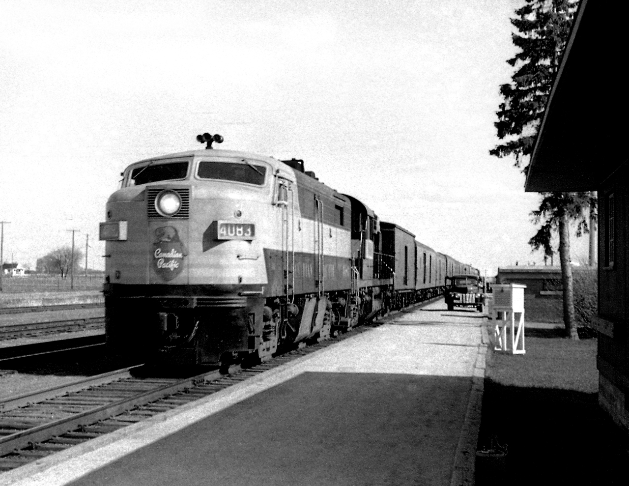 CP's westward Dominion, reduced to a primarily mail and Express train, led by an Alco FPa-2 a rarity in western Canada makes a stop at Virden. The ancient even by 1964 standards on the platform   belongs to the Post Office contractor. Express business was big, the Purolators, UPS, FedEx of the time when the railroads were the lifeblood on goods transportation.