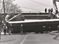 During the night of November 16, 2002 as a stopped 69-car Southern Ontario Railway train was waiting to proceed on the Dundas Subdivision from the Hagersville Subdivision, it was struck by a vehicle at the Stanley Street crossing and became instantly lodged. Shortly after, the crew received their signal and began to move unaware of what was to come, as the vehicle was dragged half a kilometer and struck a concrete bridge quickly catching it on fire. As a result, the last eight cars on the train had derailed, tumbling down embankments into nearby residential backyards as well as onto Rawdon Street. One tanker had crashed into the side of a home on Stewart Street, caving in the wall of a woman's bedroom, coming to rest less than one metre from her head. The woman was luckily unhurt, while the driver of the vehicle unfortunately perished during the incident. Luckily all of the derailed cars were virtually empty, except for some butane residue, and probably averted a deadlier disaster in the city.

A day after the derailment a friend and I ventured down to see the aftermath and were able to get fairly close to the scene. I snapped some frames of the tanker that had come to rest on the street on black and white as I had a roll of film in the camera that I was using for a photography class in college at the time. 


