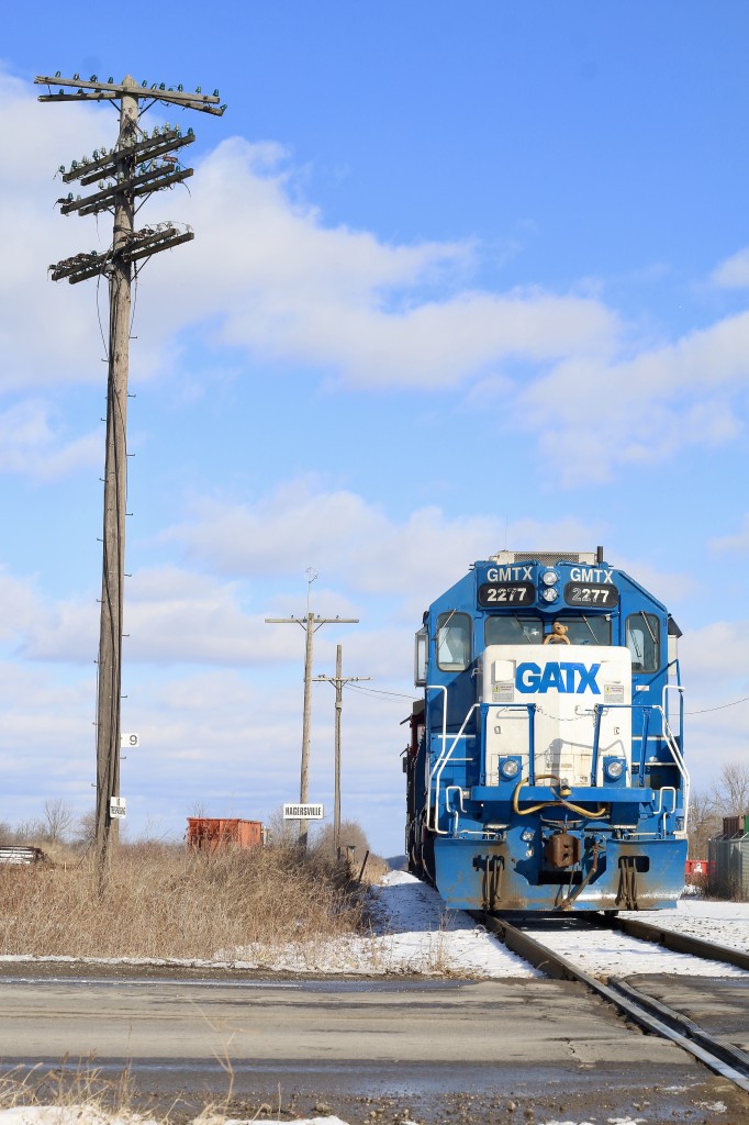 If this old telephone pole could talk, I can only imagine the stories it could tell. It has seen the transition from steam to diesel, the passage of countless trains, not just over CN's line but the once mighty double track Canada Southern that has since faded into history. Trains from not just CN but also Conrail, Penn Central, New York Central, CASO, Amtrak, CSX, Chessie System, C&O and Pere Marquette just to name a few have all hammered through the diamonds once located to the right of this old pole with its severed communication wires. It has out lasted both CN and CASO stations once located here as well as the old tower that once protected the junction. This day GMTX 2277 (a former Long Island RR GP38) rests with the rest of its consist briefly while its crew take a break in the new office after a run from Brantford. In a little while the power will take a cut of empty centre beams north to an industry north of town.