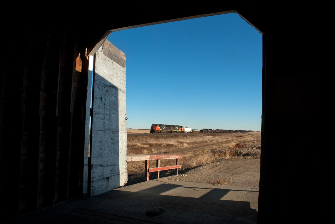 CN 301 is framed by the grain elevator door at Leney Saskatchewan.  The elevator like many others is no longer a Pool elevator, but rather is privately owned and used to store protect between harvest and trucking it to a larger inland terminal to be loaded on railcars.