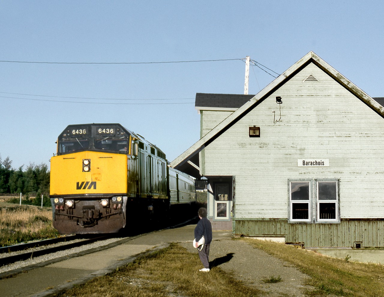 Via's eastbound "Chaleur" pulls into the station at Barachois, while someone waits for an detraining passenger