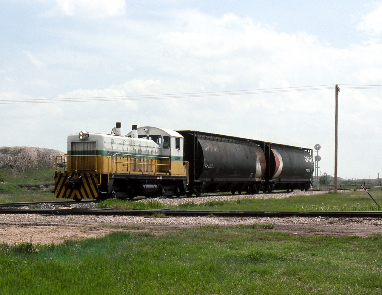 Bienfait Coal Co.'s ex MILW EMD TR4a 5706 with 2 cars of coal fines used in making charcoal BBQ briquettes crosses the the CN Lampman Subdivision on its way to the CPR Yard. The mine, formerly the Manitoba and Saskatchewan Coal co. shipped unit trains to Atikokan Ontario and Brandon Manitoba until steam generation was discontinued in early 2000's by both Manitoba and Ontario. Mine still serves the mine mouth Shand Power plant near Estevan but little moves by rail anymore from the once very busy Souris River coal fields around Estevan