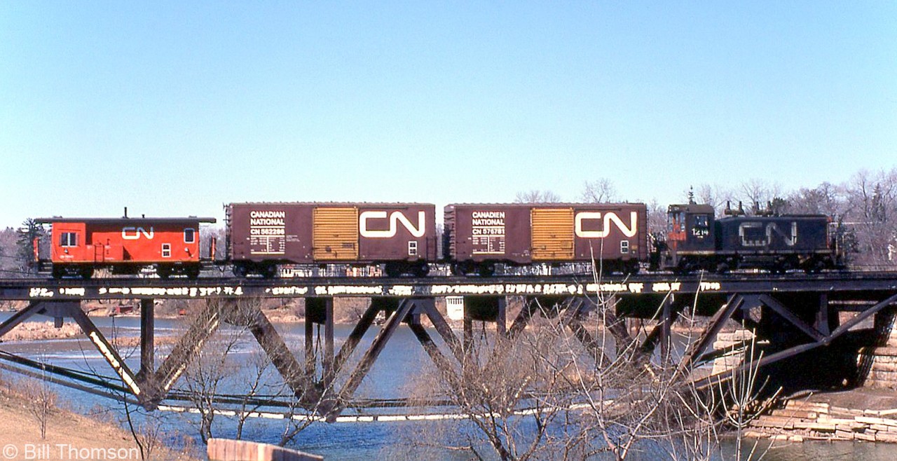 CN SW1200RS 1214 handles a short local freight, and is seen crossing the Credit River Bridge in Port Credit during March of 1981. Two 40' boxcars with yellow doors (for newsprint and other high-class merchandise) trail the power, with one of CN's unique transfer cabooses bringing up the rear.