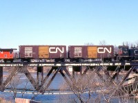 CN SW1200RS 1214 handles a short local freight, and is seen crossing the Credit River Bridge in Port Credit during March of 1981. Two 40' boxcars with yellow doors (for newsprint and other high-class merchandise) trail the power, with one of CN's unique transfer cabooses bringing up the rear.