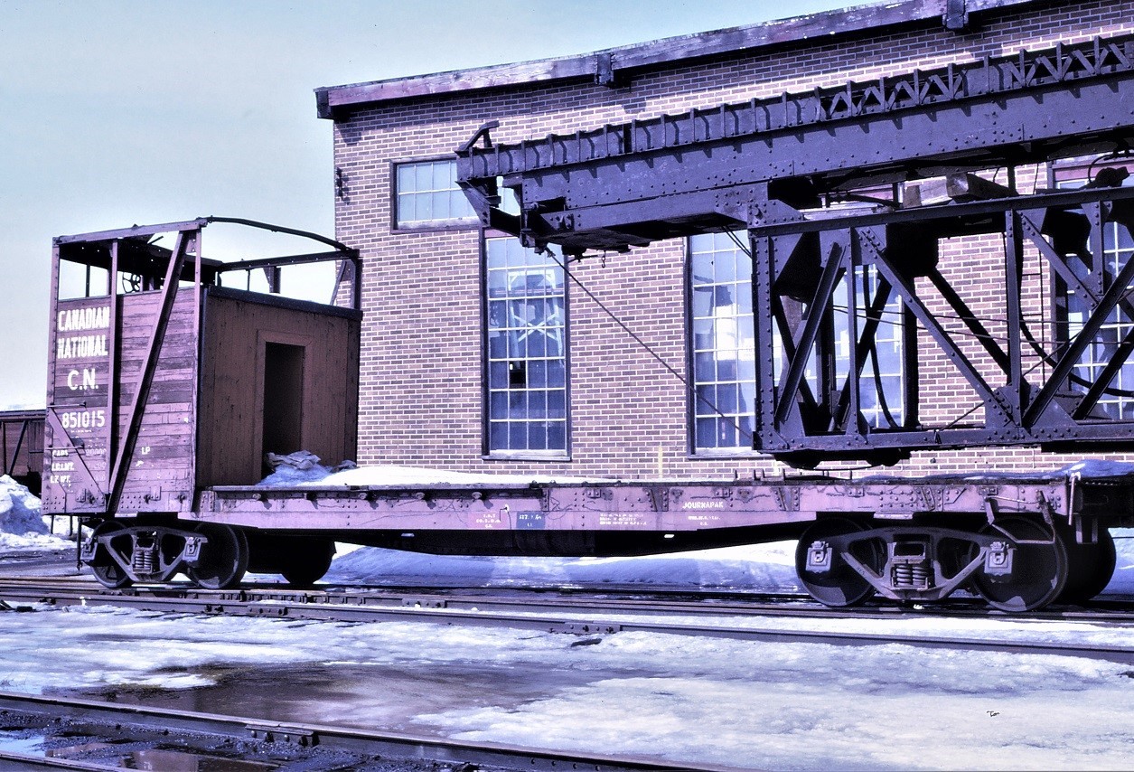Parked beside the roundhouse in Capreol, Ontario is this interesting piece of work equipment.  Starting life as a 40 foot wood sided steel under frame box car sometime in the mid 1920s, it was converted in the 1960s to a roofless box car with extended sides and used in wood chip service.  It was subsequently converted to this boom car to be used with CN pile driver 50825.  Note that the car still carries its revenue service car number.  The high brake wheel is visible through the now removed extension.
