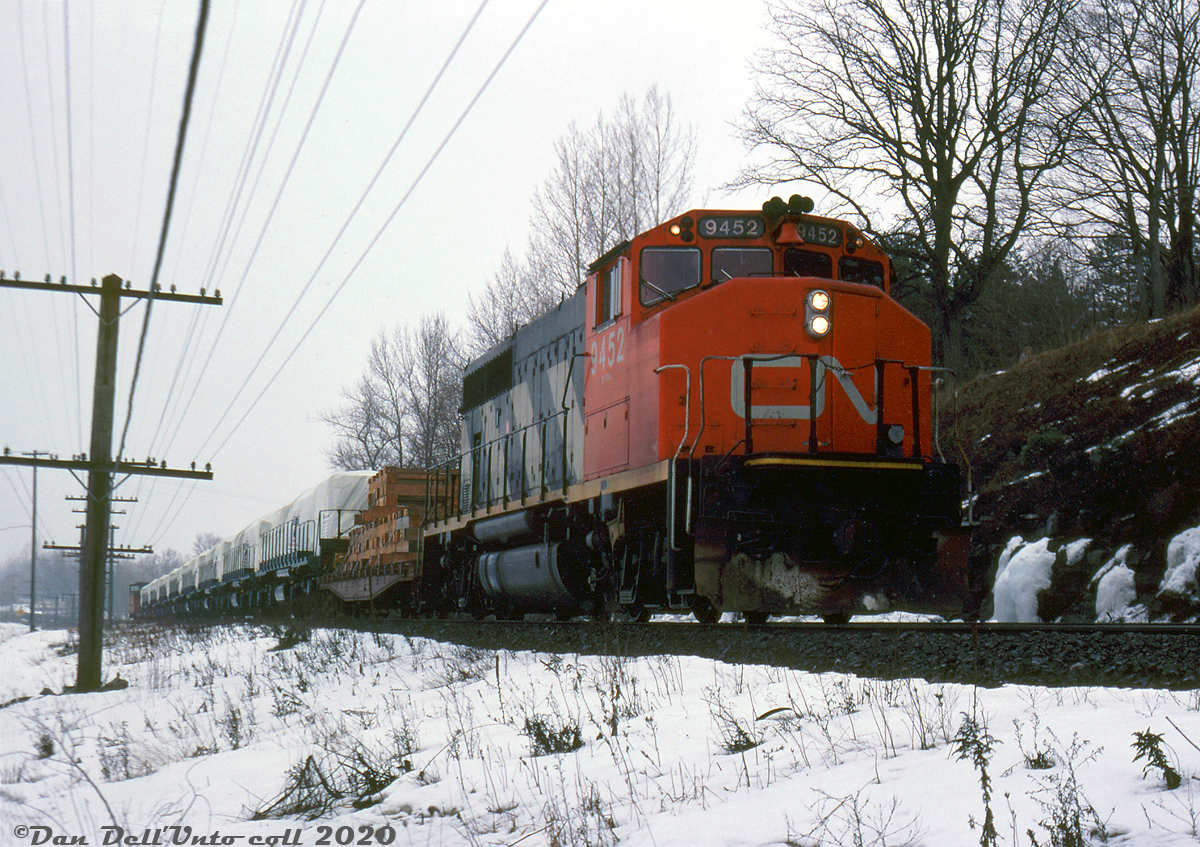 CN GP40-2L(W) leads a short export special train eastbound on CN's Kingston Sub, passing through Collins Bay just west of Kingston. Noted as the "Ayatollah Extra" by the photographer, the trailing eight units are GMD-built GT26CW-2 units bound for the east coast for export to Iran, for the Iranian Islamic Republic Railways. Part of a 1984 order for 70 units from EMD, 60 were built at GMD's London, Ontario plant between December 1983 and July 1984 as units 60.915-60.974 (an untarped example here).

Hughes W. Bonin photo, Dan Dell'Unto collection slide.