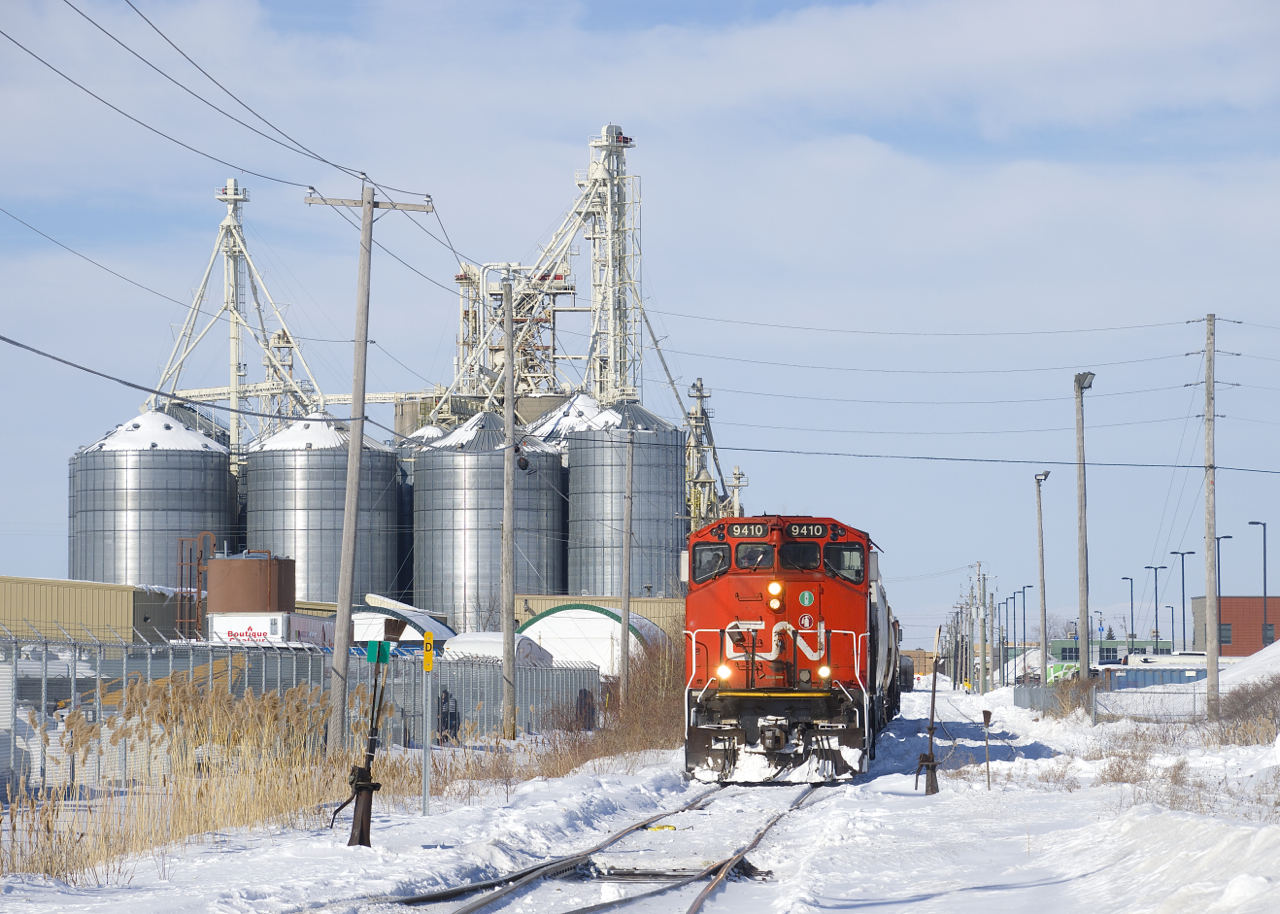 CN 522 is doing switching at Nova Grain, situated just off the Rouses Point Sub in Saint-Jean-sur-Richelieu. CN 9410 is at the front of a cut of cars, and CN 9523 is out of sight at the other end.