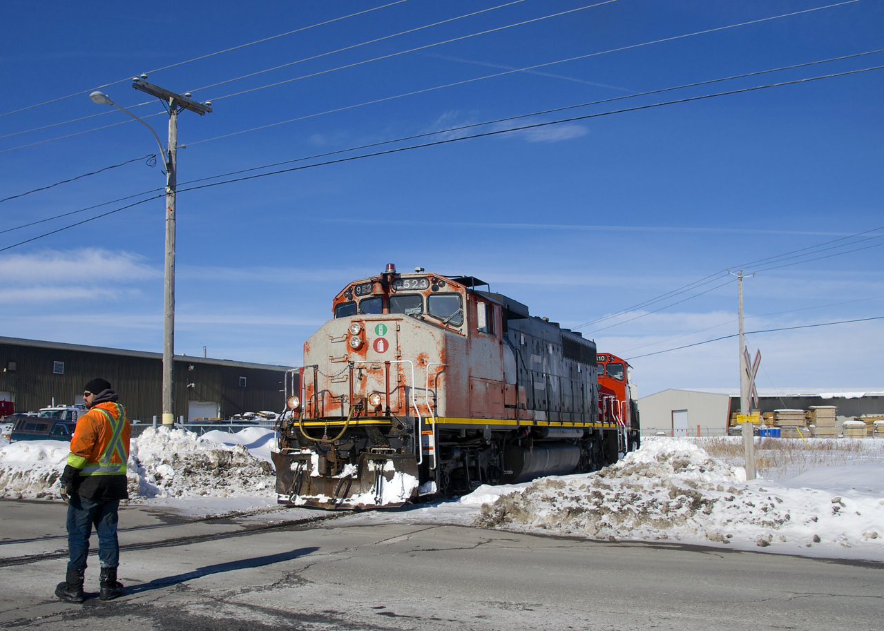 CN 522 has finished its work at Nova Grain and is about to head back to Southwark Yard as a crewmember flags the Rue Gaudette crossing. Power is CN 9523 and CN 9410.