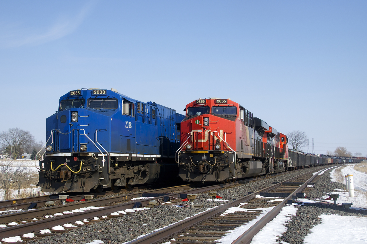 Two trains (M37721-06 & M32121-06) are parked near a crossing at MP 202.77 of CN's Kingston Sub, unable to continue west due to a protest on CN's main line along Tyendinaga Mohawk territory at the time. Apparently the line has reopened this evening. Of note is that GECX 2038 will soon be repainted into CN colours and receive a CN number.
