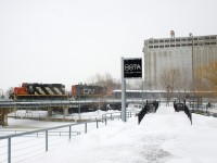 CN 4139 & CN 7250 are inbound into the Port of Montreal with a dozen cars on a snowy afternoon as they pass the entrance to the Bota Bota spa.