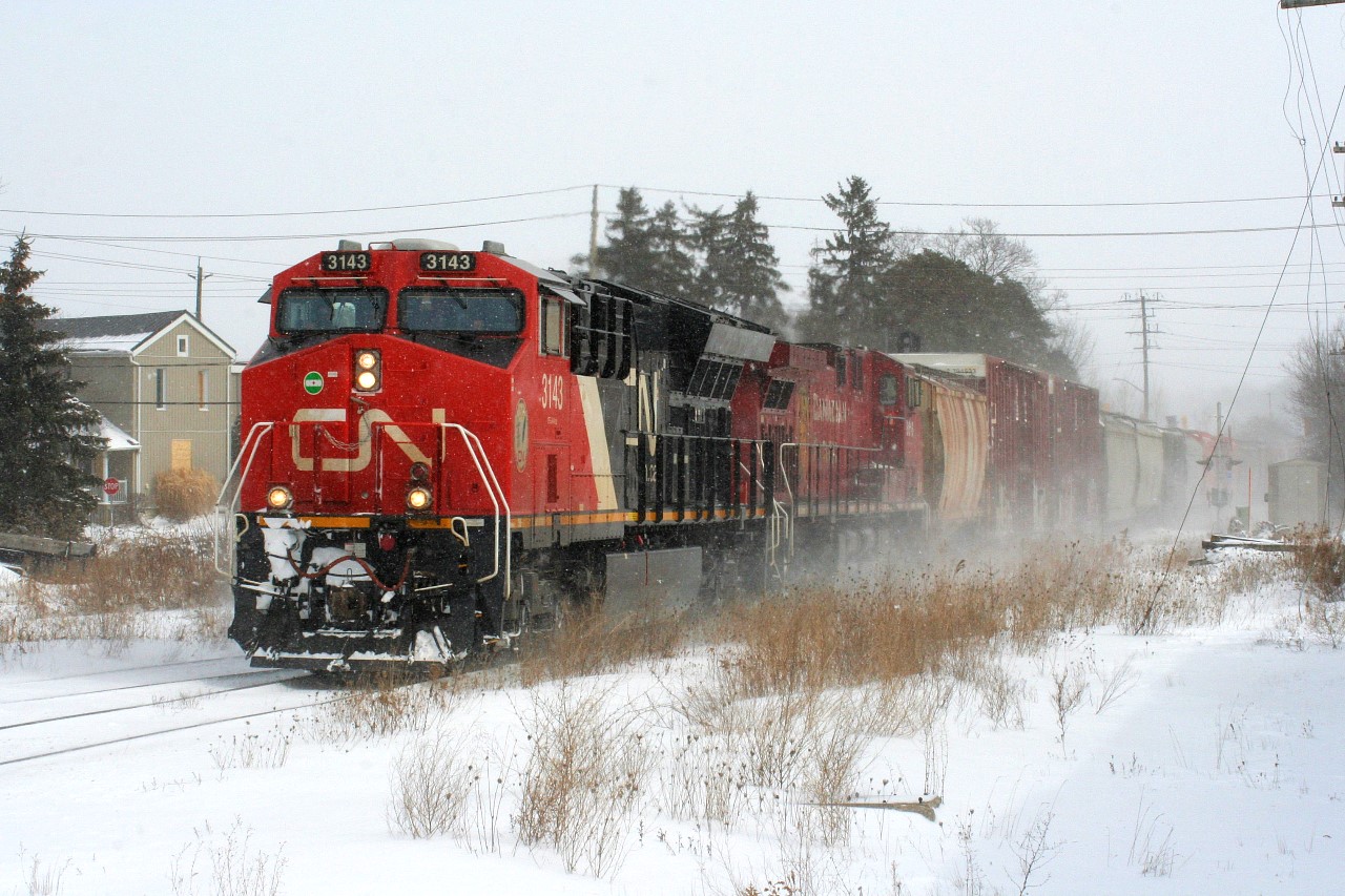 On Friday morning I awoke to the news that CN 533 had died the previous night in Kitchener and the trailing unit was CP 8616. While that was pretty historic in itself, I had to head to work in Baden, which is situated just west of Kitchener, with thoughts of taking a bit of an extended lunch and hopefully maybe catching the power laying over if it was still there. That plan went out the window rather quickly as it was determined that CN L540 would take the two GE's and a block of cars west to Stratford to lessen the congestion in a full yard at Kitchener. While it was rare enough for CN L540 to venture west of Kitchener,
it was even more layered as it would take 533's power, with one unit being CP 8616. Luckily I'm fortunate as my boss understood that I needed to take an extended break to witness a bit of history on the Guelph Subdivision. So during a brief lull between snow squalls, CN L540 is seen crossing Mill Street in Baden as it heads west to Stratford powered by CN 3143 and CP 8616.
