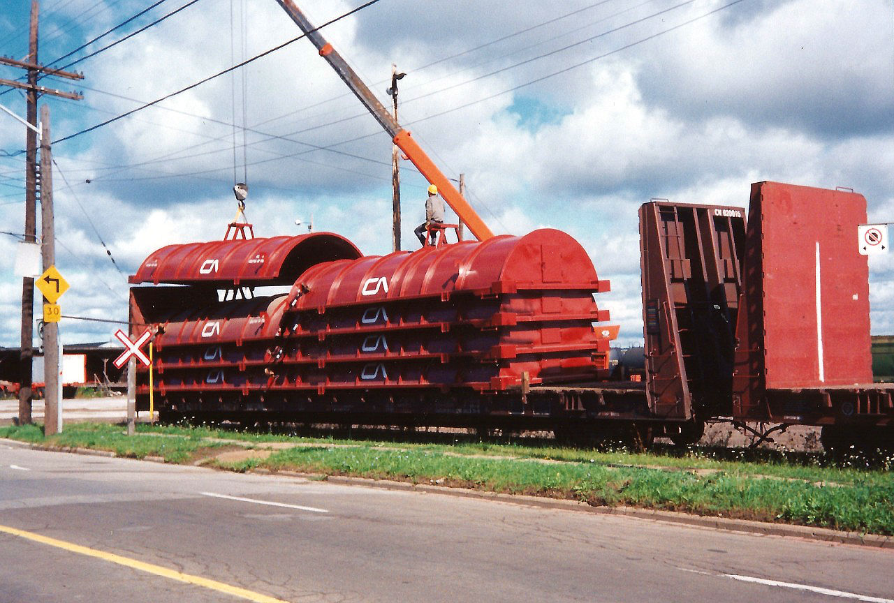 Brand new covers for CN gondolas are being cautiously unloaded from bulkhead cars at CN’s Stuart Street Yard in Hamilton. Once unloaded the covers were placed on cuts of awaiting gondolas that were set-off in the yard.