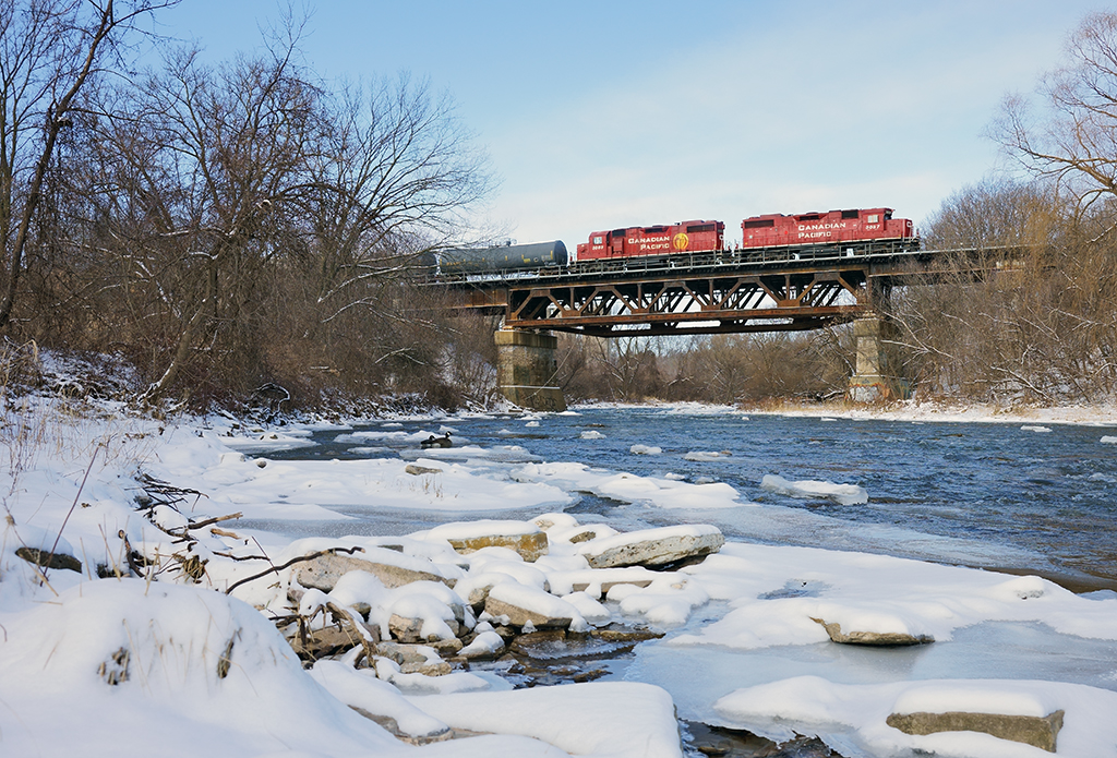 A pair of GP38's head east over the credit river bridge with 8 cars from the interchange at Streetsville.