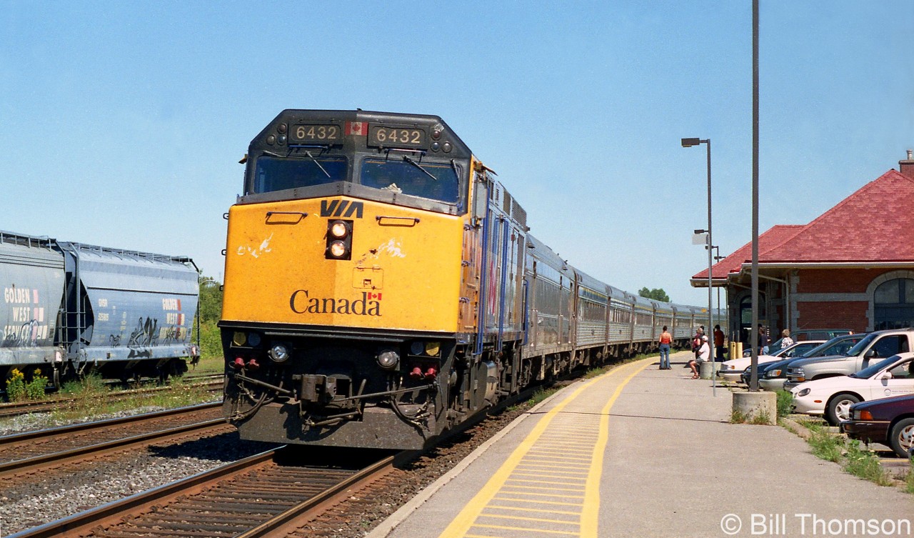 VIA train #45 pulls into Cobourg station on a sunny afternoon, with F40PH-2 6432 in the lead followed by a string of stainless steel Budd passenger cars.