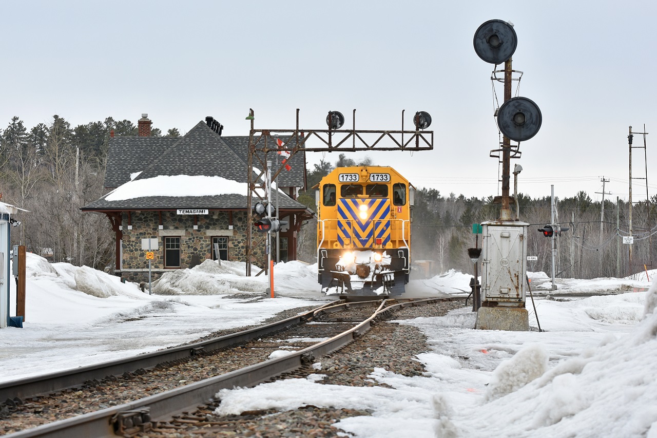 With the sand on, ONR 214 heads South through the mile 71.7 deactivated GRS searchlights next to the restored 1907 Temiskaming and Northern Ontario Railway built depot