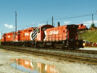 Multi-marks reflect in a late summer puddle as a CP hump set takes a rest between shifts with units 1558, 1625 and 6700 at CP's Agincourt yard in Toronto. In the background, CP 1534 and another set of power busily continues the assignment of humping and sorting cars for destinations across Canada and the US. 