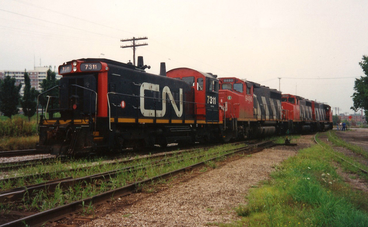 CN 421 is viewed waiting at the Kitchener yard for the 15:30 Kitchener Job to return from the Huron Park Spur with their lift of newly built frames from the Budd Plant. 421's consist included; 9560, 9620, 9490 and 7311. August 16, 1993.