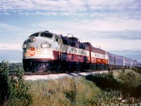 Canadian Pacific FP7 1401 and FP9 1413 head up the northbound Toronto-Sudbury leg of The Canadian, on CP's MacTier Subdivision at Tottenham ON. This was taken during a fantrip of CPR 2857 to Port McNicoll on June 5th 1960, so this may have been during a meet or photo stop along the line, possibly to the south of Tottenham station before the trip back to Toronto.<br><br>Trailing the two F-units and baggage-dormatory are two U-series tourist sleepers, part of a group of 22 former P-series heavyweight sleeping cars that were re-clad in stainless steel fluting by CP to match their new Budd-built equipment, in order to provide more standard tourist sleeping accomodations. They were retired and scrapped around the mid-60's when CP's passenger service dropped off. The rest of the train consist of the classic Budd stainless steel equipment in its as-built appearance, adorned with maroon letterbands and beaver shields. Most of the fleet is still in daily service on VIA Rail today.<br><br>This CP 1401 was the "original" unit: built as 4100 and part of the last order of FP7's CP ordered in 1953 (units 4099-4103). About a year later, they were regeared for 89mph and renumbered as 1400-series units for service on CP's new transcontinental passenger train "The Canadian", and 4100 became 1401 (they were joined by an order of 11 similar looking FP9's including trailing unit 1413, and other 4000-series units renumbered as 1400's). Unlike most other units that made it to VIA or were renumbered back into the 4000-series numbers, 1401 and F9B 1906 were involved in a wreck of The Canadian near Terrace Bay ON, when it hit a washout on April 17th 1965. Photos of the wreck show that lead unit 1401 slid down the embankment and its rear end was demolished by trailing 1906. Both were later traded in to GMD on new GP35 units.<br><br>And the current iteration of CP 1401? When CP was acquiring power for its Royal Canadian Pacific in the late 90's, they acquired their own ex-CP 1400 back, and a former CN FP9 (6541) that they renumbered above it as 1401 (plus an ex-CN F9B that became 1900).<br><br><i>Original photographer unknown, Dan Dell'Unto collection slide and photo restoration (from a pretty faded duplicate).</i>