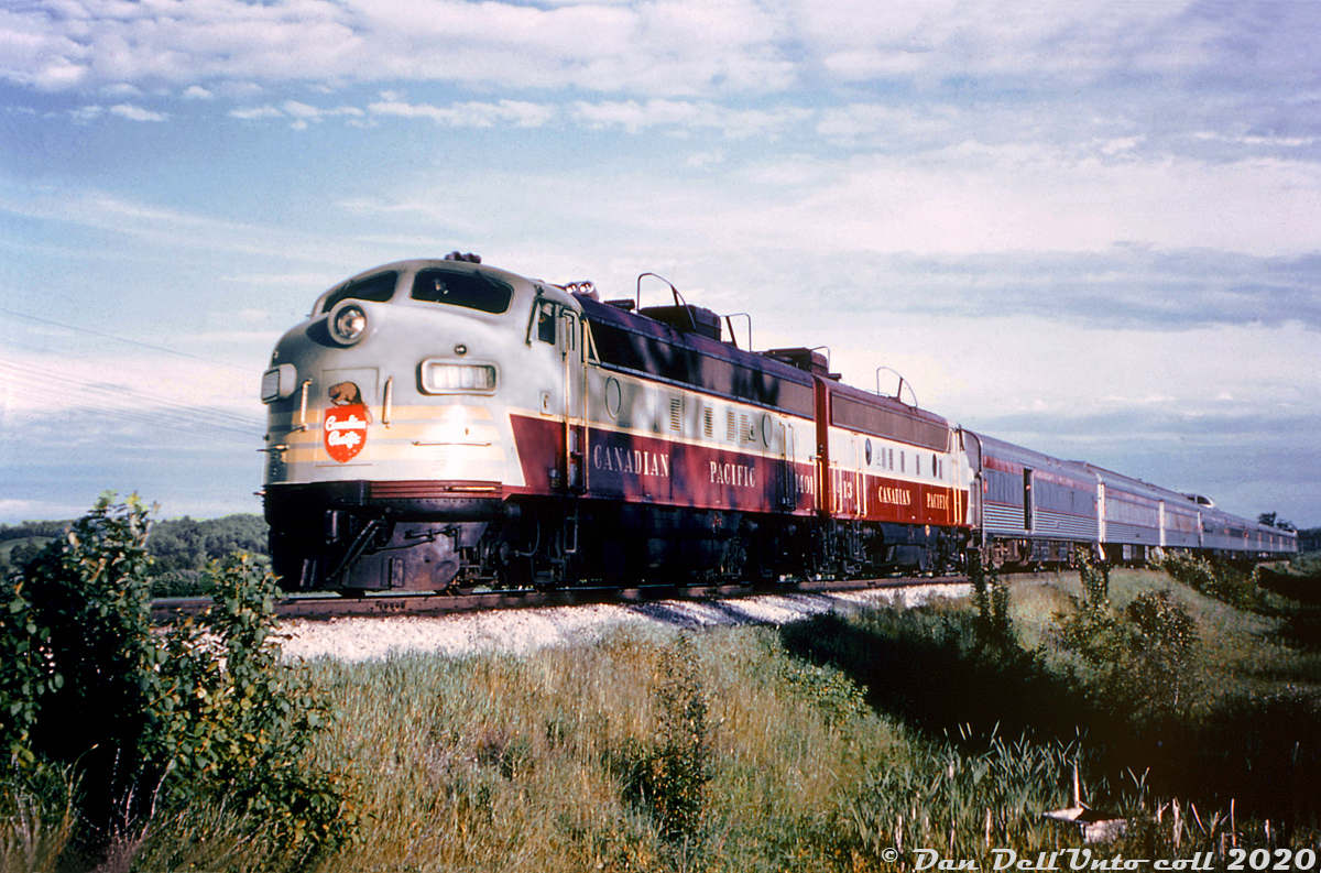Canadian Pacific FP7 1401 and FP9 1413 head up the northbound Toronto-Sudbury leg of The Canadian, on CP's MacTier Subdivision at Tottenham ON. This was taken during a fantrip of CPR 2857 to Port McNicoll on June 5th 1960, so this may have been during a meet or photo stop along the line, possibly to the south of Tottenham station before the trip back to Toronto.Trailing the two F-units and baggage-dormatory are two U-series tourist sleepers, part of a group of 22 former P-series heavyweight sleeping cars that were re-clad in stainless steel fluting by CP to match their new Budd-built equipment, in order to provide more standard tourist sleeping accomodations. They were retired and scrapped around the mid-60's when CP's passenger service dropped off. The rest of the train consist of the classic Budd stainless steel equipment in its as-built appearance, adorned with maroon letterbands and beaver shields. Most of the fleet is still in daily service on VIA Rail today.This CP 1401 was the "original" unit: built as 4100 and part of the last order of FP7's CP ordered in 1953 (units 4099-4103). About a year later, they were regeared for 89mph and renumbered as 1400-series units for service on CP's new transcontinental passenger train "The Canadian", and 4100 became 1401 (they were joined by an order of 11 similar looking FP9's including trailing unit 1413, and other 4000-series units renumbered as 1400's). Unlike most other units that made it to VIA or were renumbered back into the 4000-series numbers, 1401 and F9B 1906 were involved in a wreck of The Canadian near Terrace Bay ON, when it hit a washout on April 17th 1965. Photos of the wreck show that lead unit 1401 slid down the embankment and its rear end was demolished by trailing 1906. Both were later traded in to GMD on new GP35 units.And the current iteration of CP 1401? When CP was acquiring power for its Royal Canadian Pacific in the late 90's, they acquired their own ex-CP 1400 back, and a former CN FP9 (6541) that they renumbered above it as 1401 (plus an ex-CN F9B that became 1900).Original photographer unknown, Dan Dell'Unto collection slide and photo restoration (from a pretty faded duplicate).