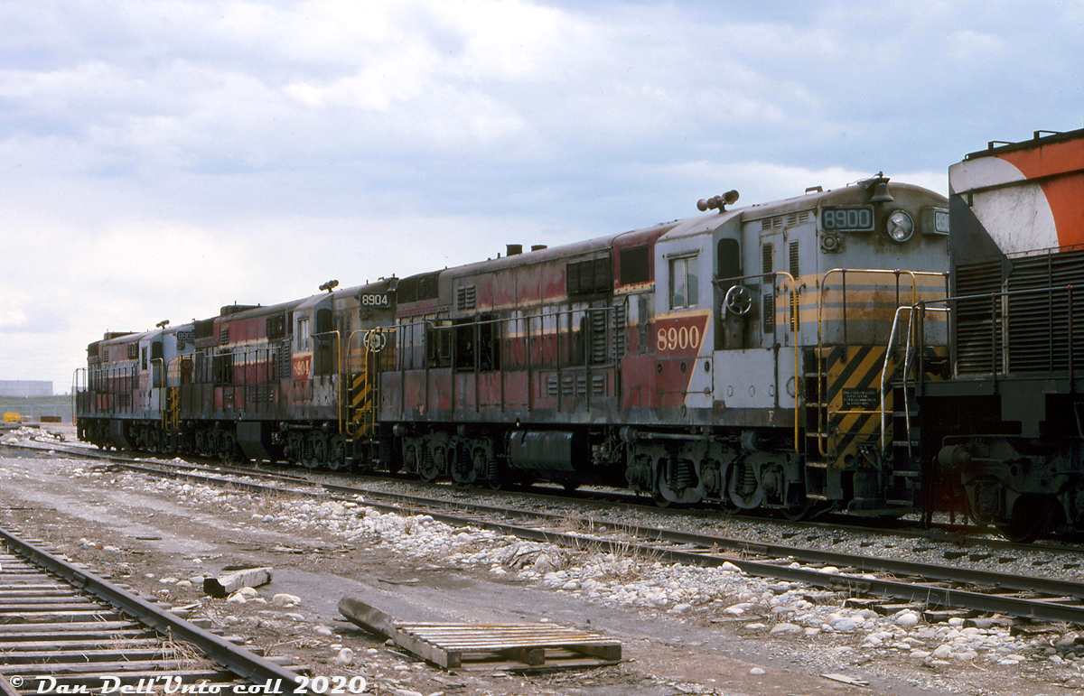 A little bit too big, and a little bit before their time: Canadian Pacific's last three Fairbanks Morse/Canadian Locomotive Company H24-66 "Train Master" units, 8900, 8904 and 8905, sit tied up at Ogden Shops in May 1976, awaiting the green light for the scrapper's torch. These ragged, aging 2400-horsepower beasts were the biggest of the big in the mid-50's and part of 21 that CP originally owned. They had last worked hump duties at the nearby Alyth Yard, paired with a chop-nosed GP9 each (and before that, were assigned Trail BC to work the steep Warfield Hill to the Cominco smelter). At this point, all of their sister 6-axle units had been retired and scrapped starting in the mid-60's.  8900 is notable as it was the first unit built for CP, jointly by FM in the US and finished at CLC in Kingston (all later units were built by CLC). It was originally outfitted with a single steam generator for dual freight/passenger service. 8904 was the final survivor of 4 units (8901-8904) delivered with two steam generators housed in a full-width short hood for passenger service (removed and narrowed once the passenger trains they worked in Saskatchewan and Manitoba were discontinued in 1960). And 8905 was the first of the standard production freight units built (8905-8920). Into the 1970's CP still had a healthy fleet of 4-axle FM/CLC units assigned to Nelson and Alyth out west, including C-Liners and smaller H16-44 units, but rising maintenance costs and a traffic downturn in 1975 spelled the end for CP's FM/CLC fleet, and they were rounded up en masse that year for scrapping. Their opposed-piston engines weren't really the best suited for railroading conditions, but their popularity and reputation in the marine industry gave railroads an easy client to sell the engines out of scrapped units to.  These three manged to last a bit longer in hump service, until they were were rounded up in December 1975 to be stored serviceable (due to their excessive exhaust fumes getting sucked into the yard office ventilation system when they idled nearby). GP7/9 and B-units replaced them on the hump jobs.  After a few months, all were noted as tied up serviceable effective May 10th 1976, and the authorization was given to scrap them not long after. Units 8900 and 8904 were cut up for scrap at Ogden Shops in August of 1976, but 8905 was set aside for historical purposes and later donated to the Canadian Railway Museum (Exporail) in Delson QC. It remains the last intact FM/CLC Train Master in existence.  Original photographer unknown, Dan Dell'Unto collection slide.