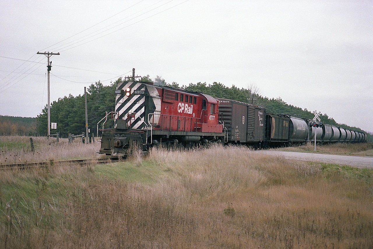 I just got to thinking to post this for those of you who knew the old CP St. Marys Sub between Ingersoll and St. Marys when it was a going concern. The southern section from Zorra to Ingersoll as I remember it was taken up in the summer of 1987, and the 24 or so miles from Zorra northward to the end at St. Marys was pulled around 1999, save for a piece to serve industry off the Galt Sub at Zorra.
This image is of CP 8777 crossing County Rd 16 just northwest of Embro on its' way to St. Marys. Not sure, but think 8777 was based out of Woodstock back then.