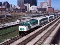 Only a few months old at the time, shiny GO Transit F40PH 511 heads up a westbound 9-car train of new bilevels and an APCU on the tail end, passing by Spadina Avenue just west of Toronto's Union Station. GO 511 was part of a six-unit order of F40PH units built by GMD at their London ON plant in April-May 1978, a change from GO's previous orders of freight GP40-2W units. New F59PH deliveries a decade later would result in GO flipping the <a href=http://www.railpictures.ca/?attachment_id=31509><b>six orphan units to Amtrak in 1990</b></a>. 511 would see another decade of service on Amtrak as their 411, and would go on to work AMT's commuter operations out of Montreal. It last saw service on the the Saratoga & North Creek Railway (via LTEX) with another ex-Amtrak F40.<br><br>The bilevel cars trailing are also new, part of the first order built by Hawker Siddeley and in service for a little over a year since introduction in March 1977. Since the first bilevel order included no cab cars, another locomotive, APCU, or old Hawker Siddeley single-level cab car had to be used on the other end in the early years.<br><br>This scene off Spadina Avenue is notable in that it's under transition: the old CN steam-era freight platforms, team tracks and yard trackage east of Bathurst Street yard are still present, but truncated for the new CN Tower's parking lot (note the yellow bridge crossing the rail corridor near TTR's John St. interlocking tower). In later years the RBC's new data center (325 Front St. W), the Metro Toronto Convention Centre and CN's L'Hotel would fill much of the vacant land along Front Street in the 80's. The usual downtown office towers of the day including the TD Centre, Royal Bank Plaza, CP Hotel's Royal York, and the CNCP Telecommunications Building (151 Front Street) are quite unobscured compared to today.<br><br><i>Bill Mischler photo, Dan Dell'Unto collection slide.</i>