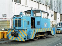 Built by the British Hunslet company, Pacific Elevators "B" would be called a diesel shunter in its homeland.<br> A more typical look for this sort of engine would be buffer and chain couplings.<br><br>
The open access door could be a sign it needs mechanical attention, but its sisters "A" and "C" can help out. <br>
A, B and C were 0-4-0 Hunslet model DH 4w, acquired new by Pacific Elevators in 1968, 1971, and 1974.<br>
"DH" suggests diesel hydraulic transmission (torque convertor), 4w might mean 4 wheels.<br>
The metal bin behind the yellow containers at left has "Hunslet stuff" written on it.<br>
Note the propane-powered forklift in the same paint colours behind "B".<br><br>
One of the Hunslets survived long enough to get repainted in Viterra's colour scheme, after they acquired Pacific Elevators in 2008.<br>
The road past the elevator had open access in 1993, but Port of Vancouver roads are restricted nowadays.